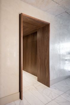 an open door in the middle of a room with white walls and tile flooring