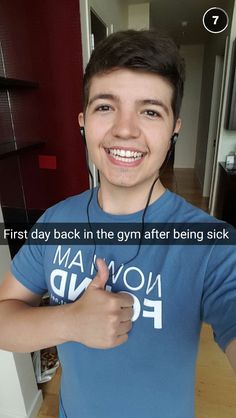 a young man with headphones on giving the thumbs up sign in front of him