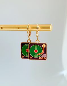 a pair of earrings hanging from a gold bar