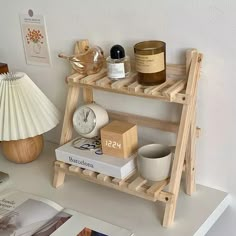 a wooden shelf with books, candles and other items on it next to a lamp