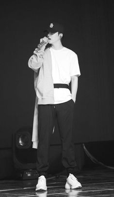 a young man standing on top of a wooden floor next to a speaker and microphone