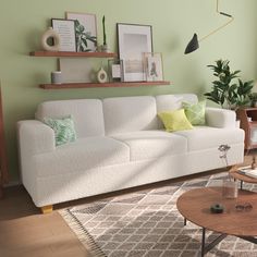 a living room with green walls and white couches, coffee table and potted plants