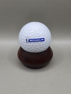 a white golf ball sitting on top of a wooden stand with the name michiln written on it