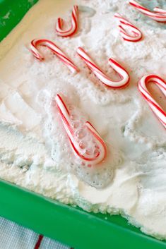 a green tray filled with white frosting and candy canes