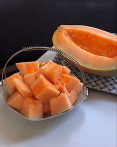 melon slices in a metal bowl on a white counter top next to a cooling rack