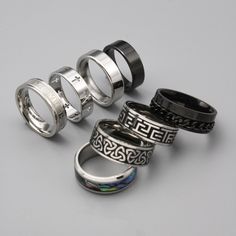 Choose from 8 of our high-quality stainless steel silver men's rings. Including: 1. Saint Cross ring 2. Celtic Knot Ring 3. Aztec Numeral Ring 4. Roman Band Ring  5. Black Classic Band Ring 6. Classic Band Ring 7.Abalone Shell Ring  8. Black Chain Ring ➤Weighty and Durable Stainless Steel ➤The perfect, versatile ring for daily wear ➤Multiple Sizes available ➤Made with High-Quality 316L Stainless Steel for a premium finish Please Note: This includes 1 ring not a full set of 8. Please pick the style that you would like from the photos. Please check our size chart in the last image before ordering. Shipping: We aim to ship your order out as soon as possible and offer Free First Class Delivery to the UK. We also offer worldwide shipping which we send with international standard delivery. Any q Cool Rings For Men Silver, Black Stainless Steel Couple Rings For Promise, Durable Silver Metal Ring, Durable Silver Promise Ring, Adjustable Silver Titanium Rings, Silver Rings For Men, Unisex Rings, Set Of Rings, Mens Ring Designs