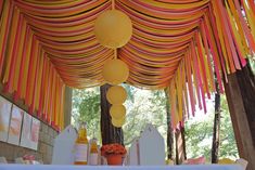 an outdoor event decorated with paper lanterns and streamers on the ceiling, along with other decorations