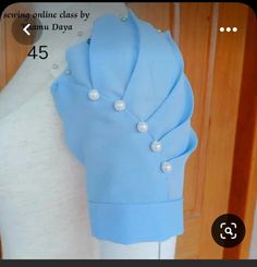 a white mannequin wearing a blue top with pearls on it's shoulders