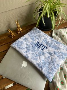 an open laptop computer sitting on top of a wooden table next to a potted plant