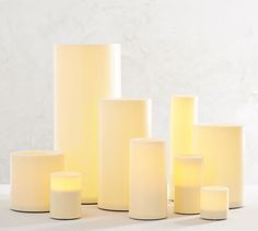 several white candles sitting on top of each other in front of a marble wall and floor