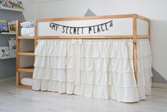 a wooden bunk bed with white ruffled bedspread and black lettering that says my secret place