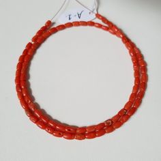 a red beaded necklace on a white surface with a name tag attached to it