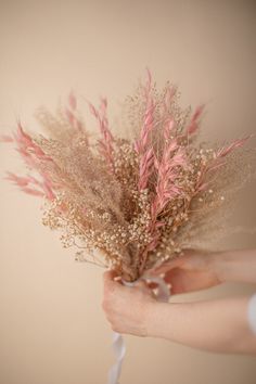 a person holding a bunch of dried flowers in their hand with the stems still attached