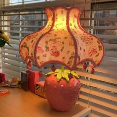 a lamp that is sitting on top of a desk next to a window with blinds