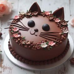 a chocolate cake decorated with flowers and a cat's face