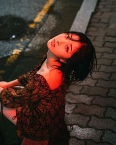 a woman is sitting on the curb with her head turned to the side and eyes closed