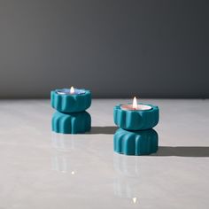 two teal candles sitting on top of a table