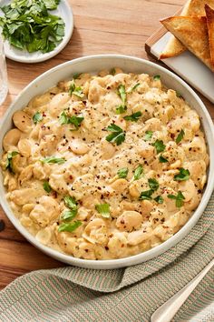 a white bowl filled with macaroni and cheese on top of a wooden table