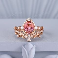 a pink diamond ring with pearls and diamonds on the sides, sitting on a white surface