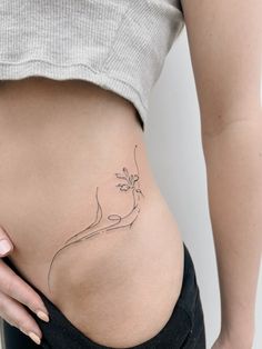 a woman's stomach with a small flower tattoo on her lower back and side