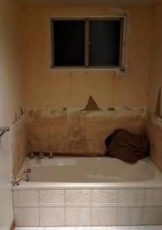 an unfinished bathroom with a bathtub, window and tile flooring being installed on the wall