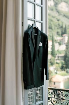 a suit hanging on a window sill in front of a balcony with an open door