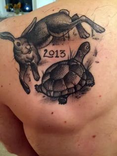 the back of a man's shoulder with two rabbits and a turtle on it