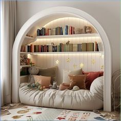 a white bed with lots of pillows and bookshelves in the corner next to a window