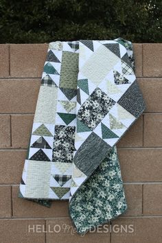 two green and white quilts sitting on top of a brick wall