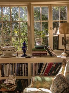 a room filled with lots of books on top of a shelf next to a window