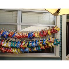 bags of chips are hanging on a clothes line in front of a window