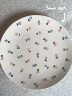 a white plate with pink, blue and green flowers on it sitting on a table