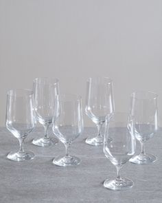 five wine glasses lined up on a table top with one empty glass in the middle