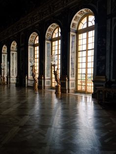 an empty room with large windows and statues on the floor in front of two doors