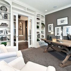 a living room filled with white furniture and pictures on the wall next to a wooden table