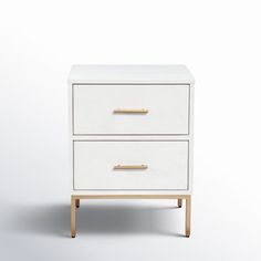 a white nightstand with two drawers and gold handles on the bottom, against a white background