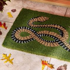 a door mat with a snake on it and leaves scattered around the area in front of it