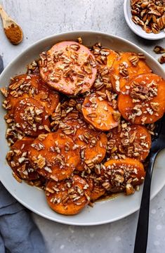 a white plate topped with sliced tomatoes and pecans next to a bowl of granola