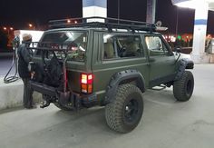 a man is filling up his jeep with gas at a gas station in the evening