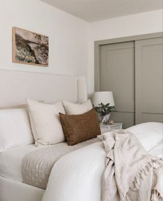 a bed with white sheets and pillows in a bedroom