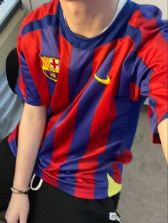 a young boy sitting in front of a keyboard wearing a red and blue striped shirt