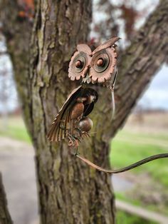 an owl sculpture is hanging from a tree