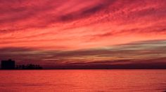 the sky is pink and orange as it sits over water