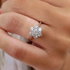 a woman's hand with a diamond ring on top of her finger and the other hand holding an engagement ring