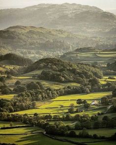 an aerial view of rolling hills and trees in the distance with mountains in the background