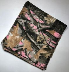 a pink and black camouflage pocket square on a white tablecloth with an image of trees in the background