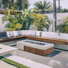 an outdoor fire pit with benches and palm trees in the backgrounnd area