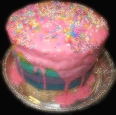 a colorful cake with sprinkles and icing on a glass platter