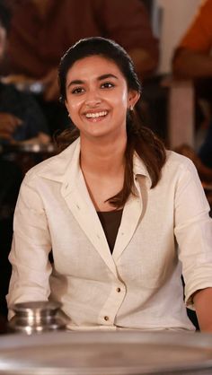 a woman sitting at a table smiling for the camera