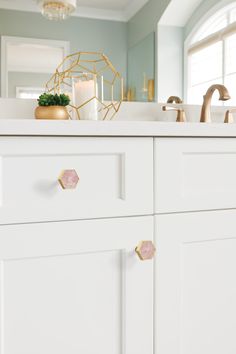 a kitchen with white cabinets and gold knobs on the handles, along with a candle holder